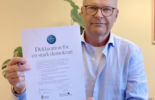 Kommunstyrelsens ordförande Jacob Käll håller upp ett signerat exemplar av åtagande för stark demokrati